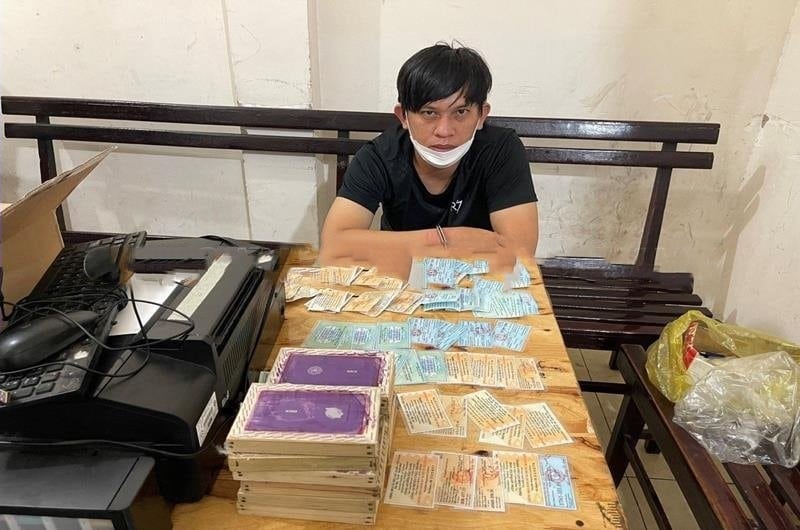 Đối tượng Nguyễn Nam Tào cùng nhiều giấy tờ đăng ký xe mô tô giả. (Ảnh:CA)